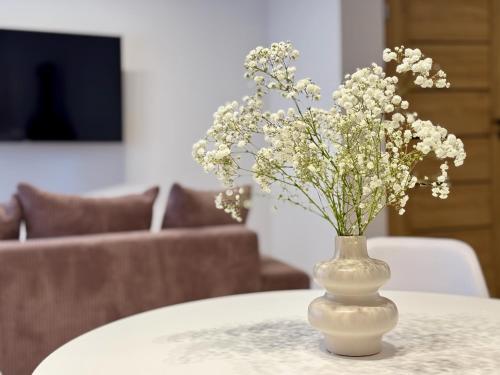 a vase with white flowers sitting on a table at Cozy Cottage in Oświęcim