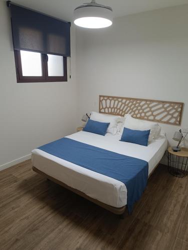 a bedroom with a large bed with blue pillows at Apartamentos AL-QAZERES LUXURY La Concepción in Cáceres