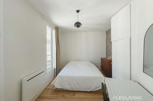 une chambre blanche avec un lit et un miroir dans l'établissement Flexliving - Studio - Durantin, à Paris