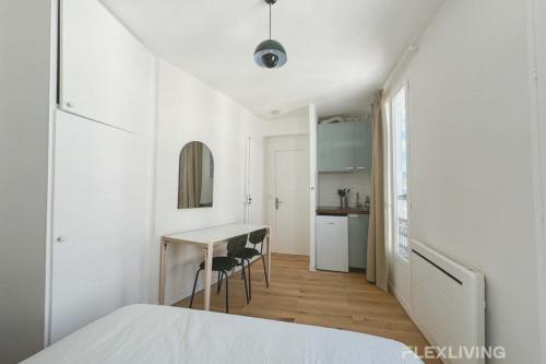 une chambre blanche avec une table et une cuisine dans l'établissement Flexliving - Studio - Durantin, à Paris