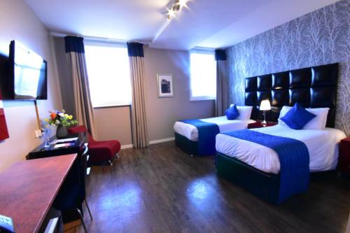 a hotel room with two beds and a television at The Royal Hotel Cardiff in Cardiff