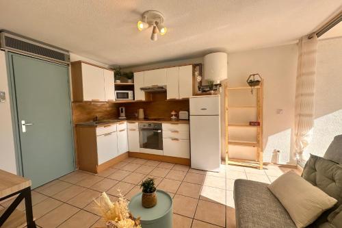 une cuisine avec des armoires blanches et un réfrigérateur blanc dans l'établissement Le Catamaran - Studio proche de la mer avec terrasse, au Grau-du-Roi