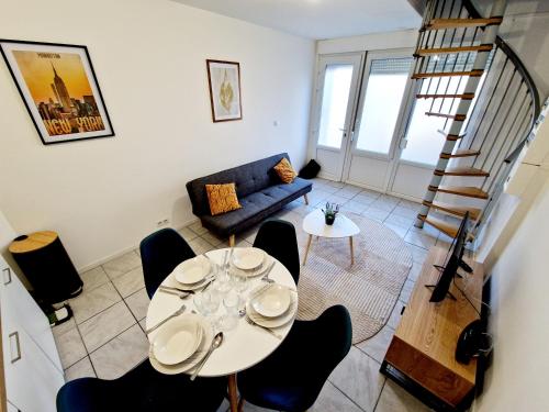a living room with a table and chairs and a staircase at Duplex tout équipé in Marpent