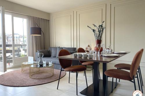 un salon avec une table, des chaises et un canapé dans l'établissement l'Elégance - Vue dégagée - Balcon - Parking, à Deauville