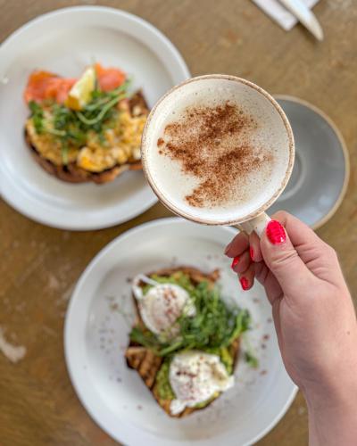 a person holding a cup of coffee next to plates of food at The Mortimer Arms in Romsey