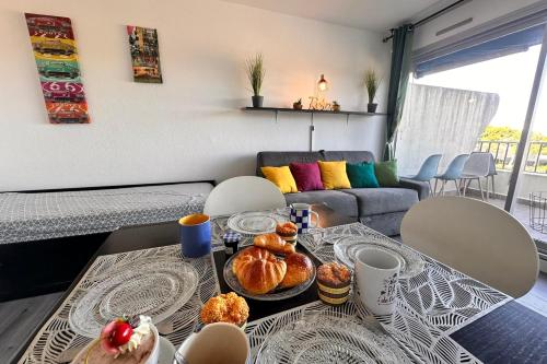 - un salon avec une table et des pâtisseries dans l'établissement Studio Les Jardins du Port Port Camargue avec piscine à 2 pas de la plage, au Grau-du-Roi