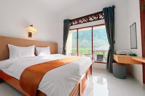 a bedroom with a large bed and a large window at Simangande View & Resto by Staigo in Ambarita