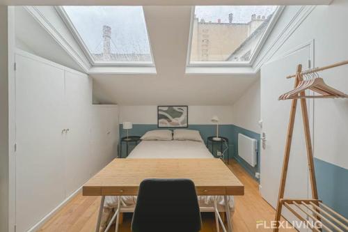 Cette chambre comprend un lit, une table et deux fenêtres. dans l'établissement Flexliving - Studio - St Dominique, à Paris