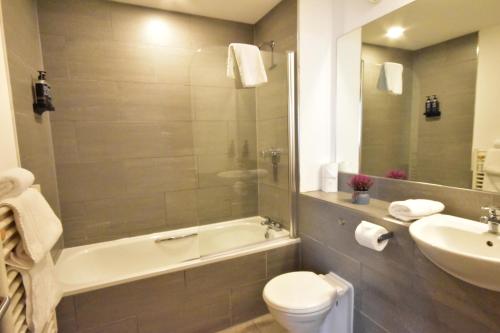 a bathroom with a toilet and a tub and a sink at The Royal Hotel Cardiff in Cardiff
