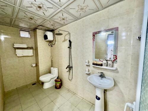 a bathroom with a sink and a toilet and a mirror at Sea Dragon Hotel Cát Bà & Aparment in Cat Ba