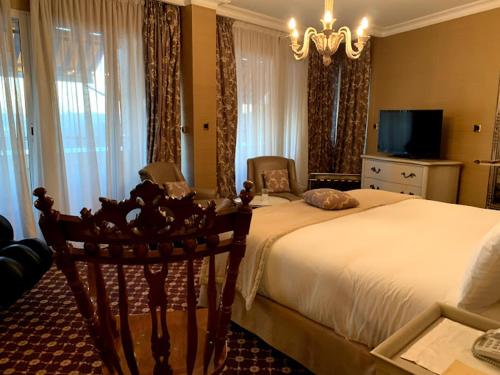 a bedroom with a large bed and a chandelier at Hotel El Djazair in El Mouradia