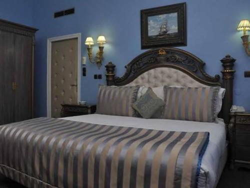 a bedroom with a large bed and a blue wall at Hotel El Djazair in El Mouradia