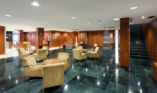 a lobby with chairs and tables in a building at Sercotel Cornellà Barcelona in Cornellà de Llobregat