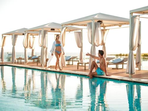 a man and a woman sitting next to a swimming pool at Zaton Holiday Resort in Nin
