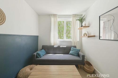 un salon avec un canapé et une fenêtre dans l'établissement Flexliving - Whole flat - Friant, à Paris