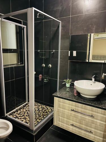 a bathroom with a shower and a sink at Laicah House in Tlokweng