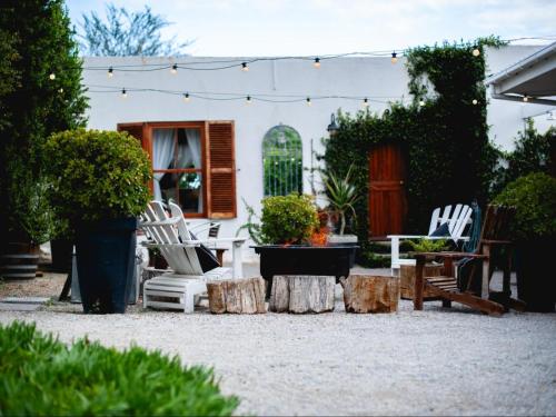 a patio with white chairs and a table and trees at Croxley Farm in Robertson