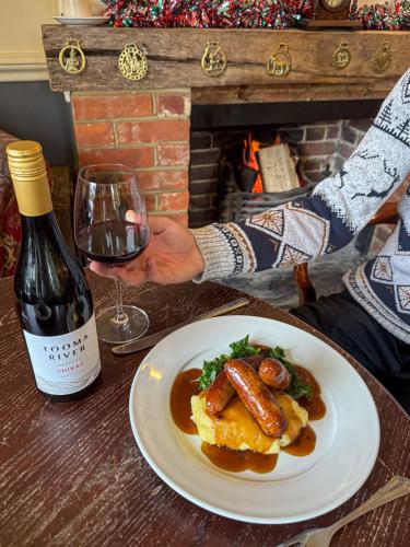 a person sitting at a table with a plate of food and a wine glass at The Mortimer Arms in Romsey