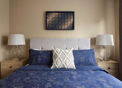 a bedroom with a blue bed with two lamps at Whimsical Haunt in West Malling