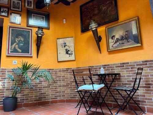 a wall with two chairs and pictures on it at La Posada de Zepeda in Jerez de la Frontera