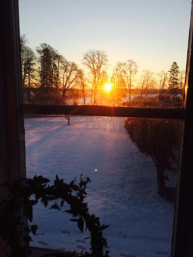 a view of the sunset through a window with snow at Brunsbo G:a Biskopsgård Hotell & Konferens in Skara