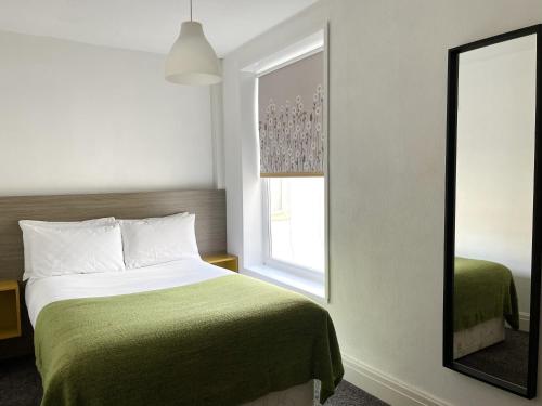 a bedroom with a green bed and a mirror at The Bawdens Holiday Apartments in Blackpool