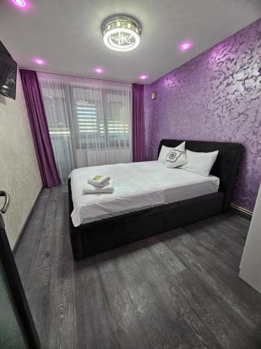 a bedroom with a large bed with purple walls at Home LCF in Brăila