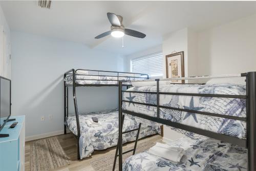 a bedroom with two bunk beds and a ceiling fan at Beach Paradise - Perfect Ocean Sunset Views with Pool & Sauna & Breakfast! in Mexico Beach