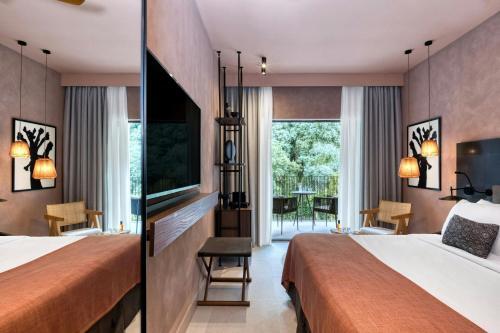 a hotel room with two beds and a flat screen tv at Domes of Corfu, Autograph Collection in Glyfada