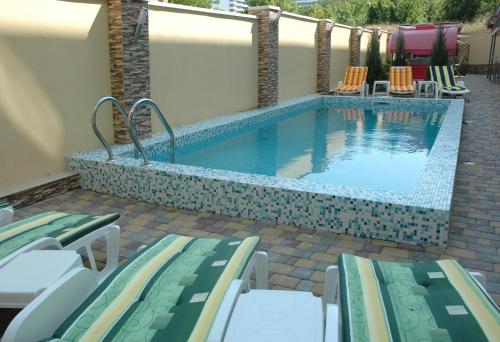 a swimming pool with lounge chairs and a swimming pool at Villa Panama in Odesa