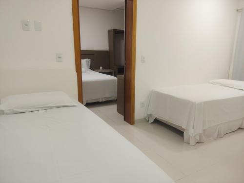 a bedroom with two beds and a mirror at Hotel e Restaurante La Carreta in Tangara da Serra