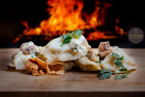 a pile of food on a table in front of a fire at Hotel Villa Bohema in Kazimierz Dolny
