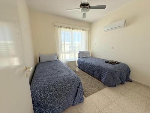 a bedroom with two beds and a ceiling fan at SeaTurtle Beach House in Paralimni