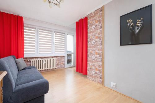 a living room with a blue couch and red curtains at Spacious Studio with Balcony in Katowice by Noclegi Renters in Katowice
