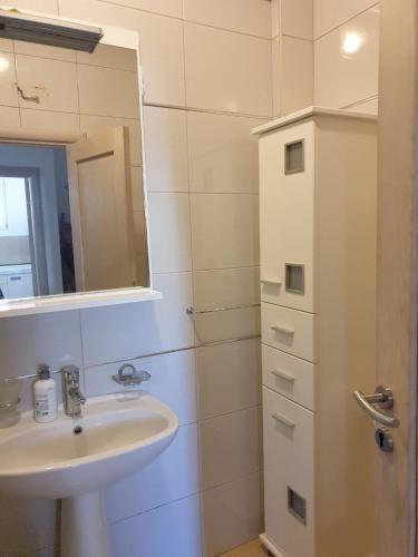 a white bathroom with a sink and a mirror at Victor Apartments in Petrovac na Moru