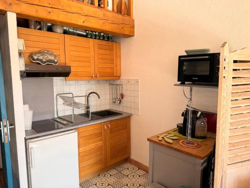 une petite cuisine avec un évier et un micro-ondes dans l'établissement Appartement avec mezzanine de vacances à 7 min de la plage, aux Lecques