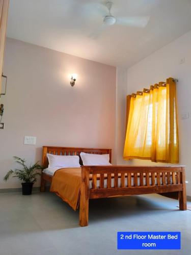 1 dormitorio con cama de madera y cortina amarilla en SRUSHTI The Peace Home, en Kolhapur