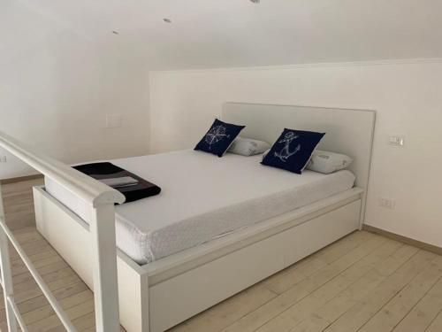 a white bed with blue pillows in a room at House on the beach Varigotti in Varigotti