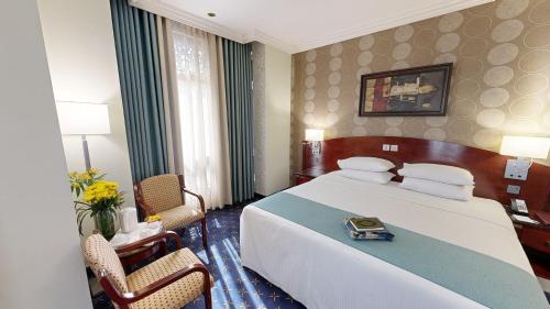a hotel room with a large bed and two chairs at Al Muna Kareem Hotel- EX LEADER in Al Madinah