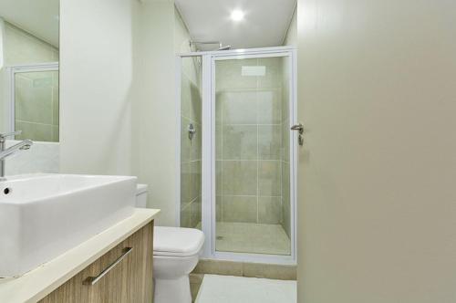 a bathroom with a shower and a toilet and a sink at The Bolton serviced apartments Rosebank in Johannesburg