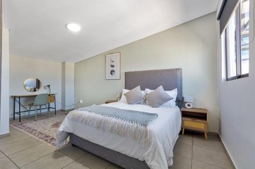 a bedroom with a large bed and a desk at The Bolton serviced apartments Rosebank in Johannesburg