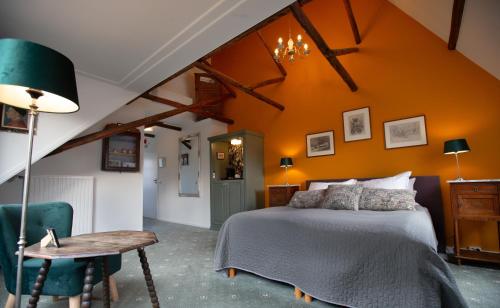a bedroom with an orange wall with a bed and a table at Stadslogement De Oude Smidse Steenwijk in Steenwijk