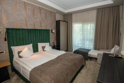 a bedroom with a large bed with a green headboard at Nora Prestige in Timişoara