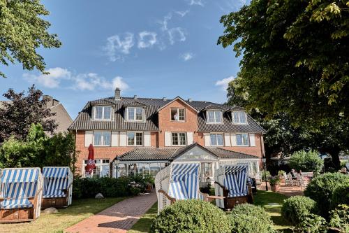 a house with two blue and white chairs in the yard at Strandhotel Strande in Strande