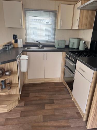 a kitchen with white cabinets and a stove top oven at Snowdon View, White Tower Holiday Park in Caernarfon