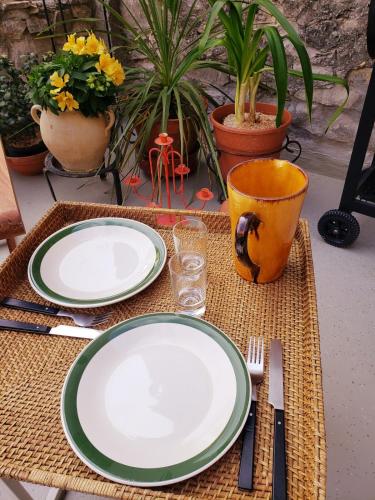 a table with plates and utensils on a table with plants at Appartement lumineux avec 1 chambre à Marsanne in Marsanne