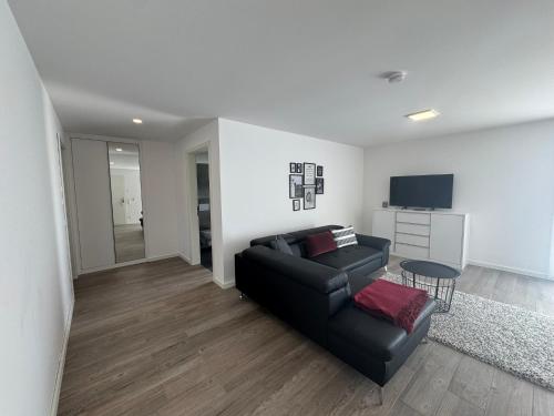 a living room with a black couch and a table at Hotel Barth in Kaiserslautern