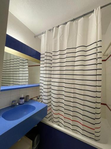 une salle de bain avec un rideau de douche et un lavabo bleu dans l'établissement Appartement Cannes, Piscine - Terrasse, Jardin Privatif - 4 Personnes, à Cannes