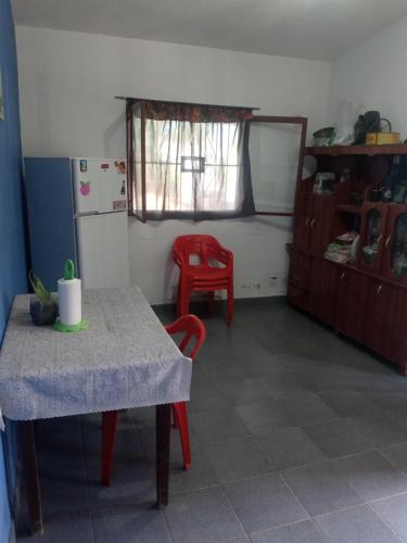 eine Küche mit einem Tisch und einem roten Stuhl und einem Kühlschrank in der Unterkunft Casa de Fin de semana in Termas de Río Hondo