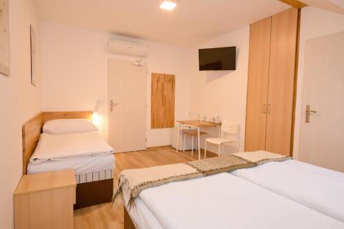 a room with two beds and a table with a television at Wellness Vila Bohemia in Prague